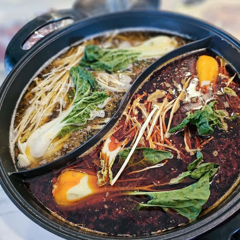 Hot pot with two broths, greens and noodles